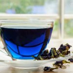 Anchan blue tea is brewed in a cup, dry clitoria ternatea flower petals lie on a saucer